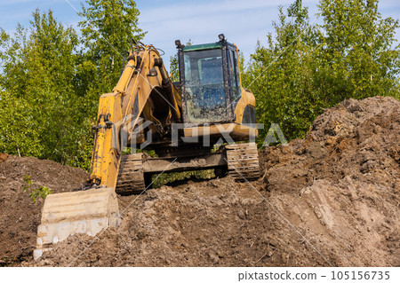 Yellow excavator works on a pile of soil Yellow excavator works on a pile of soil 105156735