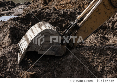 Dirty excavator bucket is on a pile of dark soil Dirty excavator bucket is on a pile of dark soil 105156736