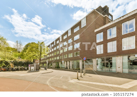 an empty street in front of a large brick building with many windows on each side and cars parked along the road an empty street in front of a large brick building with many windows on each side and cars parked along the road 105157274