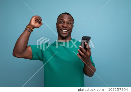 young handsome african man dressed in t-shirt uses smartphone for social media on isolated young handsome african man dressed in t-shirt uses smartphone for social media on isolated 105157294