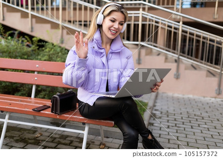 freelancer girl broadcasting in the city using a portable laptop and headphones freelancer girl broadcasting in the city using a portable laptop and headphones 105157372