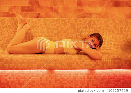 Young woman in a white swimsuit is lying in a salt room. Young woman in a white swimsuit is lying in a salt room. 105157429