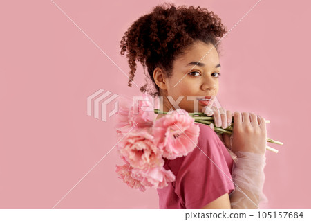 Beautiful african girl holds a bouquet of pink flowers near her face 105157684