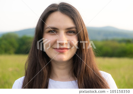 Portrait of a 30-year-old brunette woman looking at the camera smiling in nature. 105158350