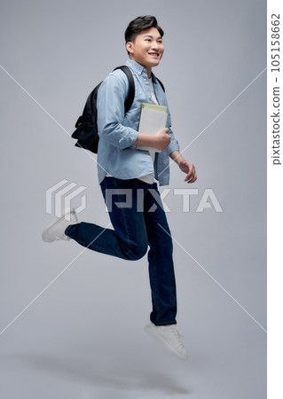 Full length shot of a tall guy holding books and jumping isolated on white background 105158662