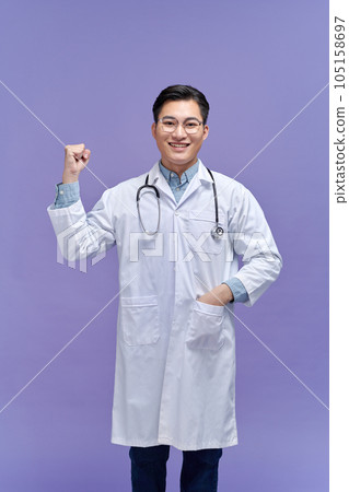 Portrait of beautiful young female doctor in white medical jacket isolated on purple background. 105158697