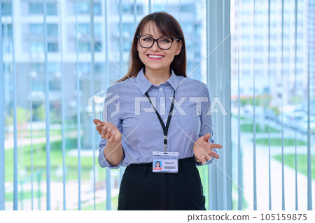 Middle aged woman with educational center id card, in office near window 105159875