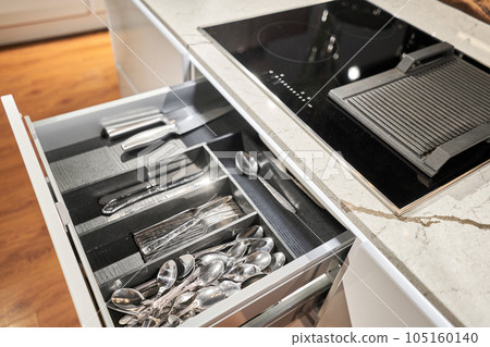Kitchen utensil cutlery drawer organizer tray with simple set of tools, minimalist order. Open drawer with different utensils and folded towels. Order in kitchen. Kitchen furniture store. Kitchen utensil cutlery drawer organizer tray with simple set of tools, minimalist order. Open drawer with different utensils and folded towels. Order in kitchen. Kitchen furniture store. 105160140