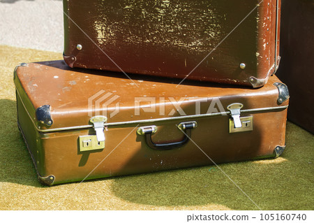 Old shabby brown suitcases on a green surface. Old shabby brown suitcases on a green surface. 105160740