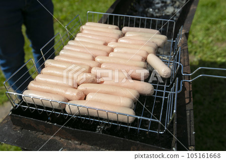 A lot of sausages are grilled on a barbecue grill for a buffet table. 105161668