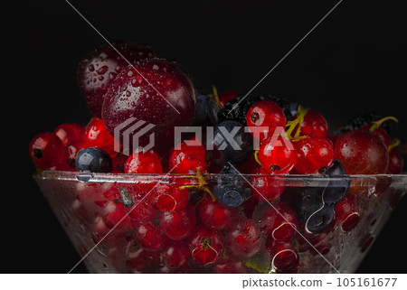 Beautiful red berries poured with water on a dark background close-up. 105161677