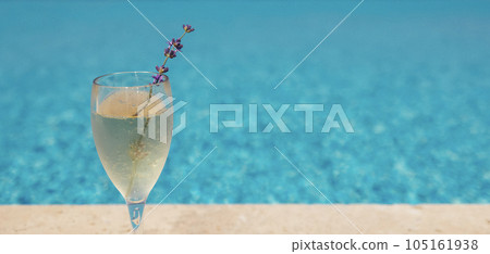 Glass of champagne with sprig of lavender against poolside at resort hotel during vacation Glass of champagne with sprig of lavender against poolside at resort hotel during vacation 105161938