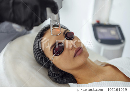 Closeup of the face of young woman undergoing laser resurfacing and peeling procedure in spa salo Closeup of the face of young woman undergoing laser resurfacing and peeling procedure in spa salo 105161939