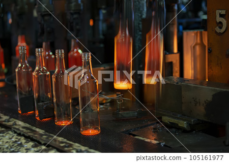 Glassworks. Glass industry. The process of making glass bottles.Molten hot glass containers on conveyor belt 105161977