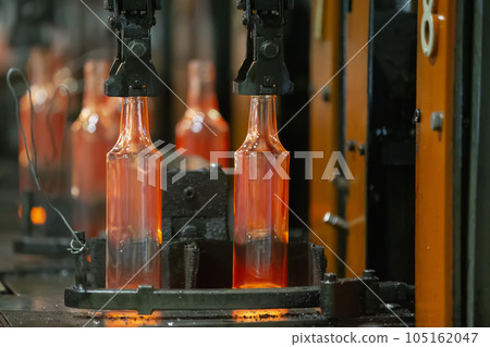 Glassworks. Glass industry. The process of making glass bottles.Molten hot glass containers on conveyor belt Glassworks. Glass industry. The process of making glass bottles.Molten hot glass containers on conveyor belt 105162047