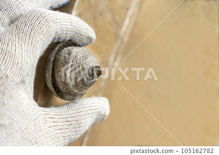 man's hand in a protective work glove removes a wasps nest 105162782
