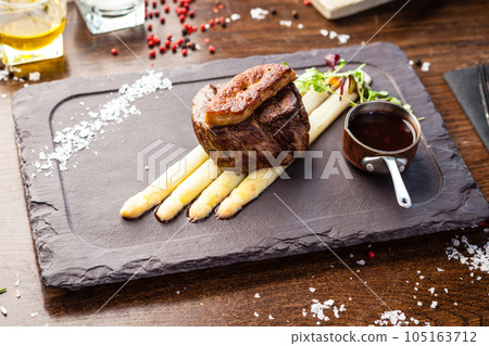 Tournedos Rossini. Foie gras, Black Angus beef tenderloin, white asparagus, red wine sauce. Delicious healthy traditional food closeup served for lunch in modern gourmet cuisine restaurant 105163712