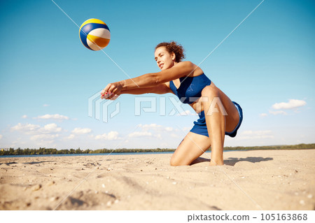 Young athletic women playing beach volleyball on warm summer day outdoors. Hitting ball with hands. Concentration Young athletic women playing beach volleyball on warm summer day outdoors. Hitting ball with hands. Concentration 105163868