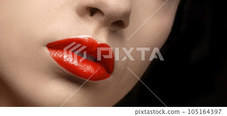 Lips with red lipstick. Red lip makeup detail. Beautiful color lipstick or gloss close-up. 105164397