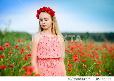 Ukrainian Beautiful girl in poppies field and wheat. outdoor portrait. Child collecting poppies and cornflower in summer field. Blooming Poppies memory symbol. 105164477