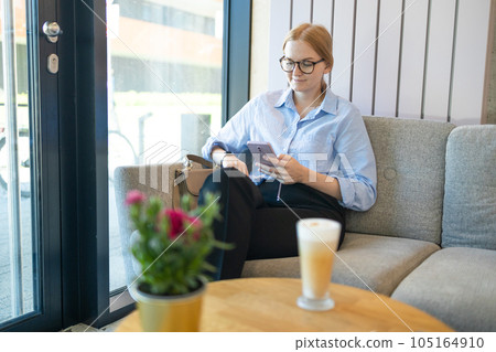 Portrait of happy young office assistant working remotely online sitting using mobile phone and texting in social networks, sitting alone Portrait of happy young office assistant working remotely online sitting using mobile phone and texting in social networks, sitting alone 105164910