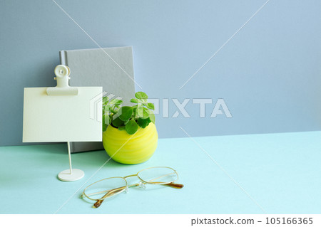 Notebook, memo pad, plant, eyeglasses on blue desk. blue wall background. workspace 105166365