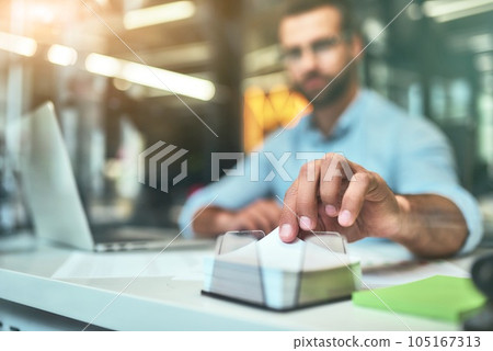 Making notes. Blurred photo of young bearded businessman taking white note paper to write something while working in the modern office Making notes. Blurred photo of young bearded businessman taking white note paper to write something while working in the modern office 105167313