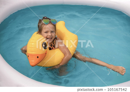 Funny laughing humorous girl having fun in the water in an inflatable mini swimming pool swimming on a circle 105167542