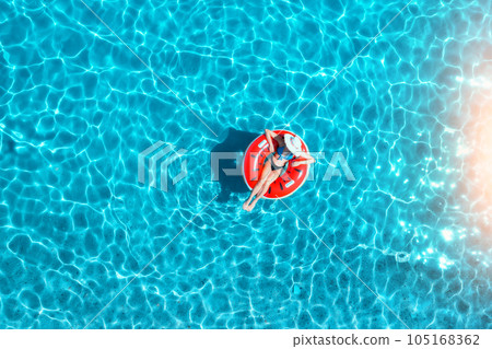 Aerial view of a young woman swimming with red swim ring 105168362