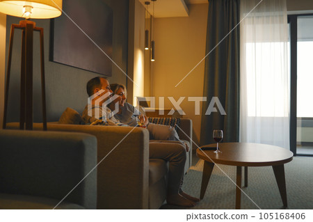 A young married couple watches TV in the evening in the cozy living room at home. 105168406