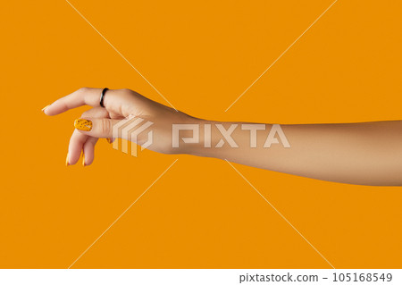 Womans hand with jewelry accessories over orange background Womans hand with jewelry accessories over orange background 105168549