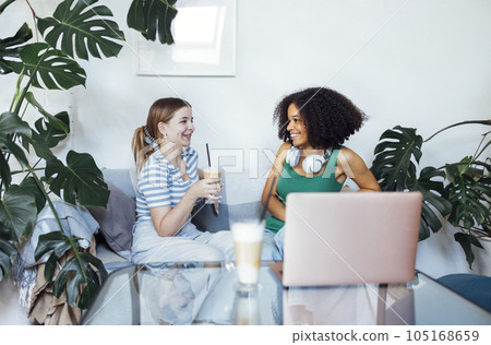 Attractive multiracial teenagers drink cappuccino and chat. Funny teen girls talk and have good time together. 105168659