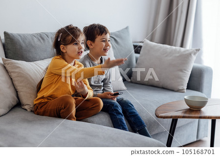 Cute girl and boy laughing and choosing cartoons in tv Cute girl and boy laughing and choosing cartoons in tv 105168701