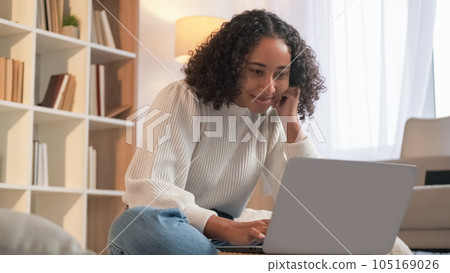 Internet connection. Remote work. Online communication. Joyful woman chatting laptop enjoying weekend indoors at home living room. 105169026