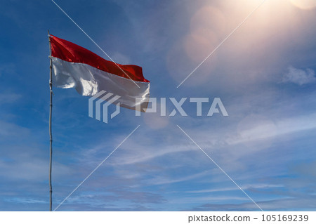 Flag of the republic indonesia with blue sky as background. indonesia flags under blue sky independence day concept Flag of the republic indonesia with blue sky as background. indonesia flags under blue sky independence day concept 105169239