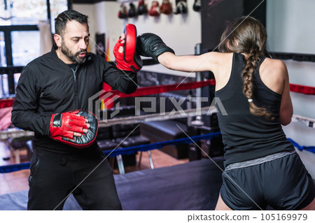 K1 50s instructor at gym. Hispanic woman punch action with gloves strength fight self-defense 105169979