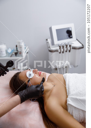 facial skin care, cosmetic facial procedure, rejuvenation procedure.cosmetologist applies mask on woman's face in a beauty salon. cosmetologist performs facial treatments for a customer at an facial skin care, cosmetic facial procedure, rejuvenation procedure.cosmetologist applies mask on woman's face in a beauty salon. cosmetologist performs facial treatments for a customer at an 105172207