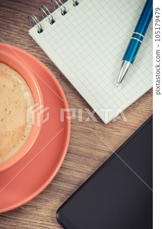 Mobile phone, coffee with milk and notepad for writing notes. Work or relaxation 105179479