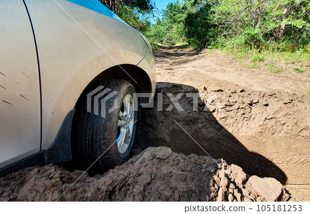 The car hit the front wheel in a deep hole on the road in the forest strip. The car hit the front wheel in a deep hole on the road in the forest strip. 105181253