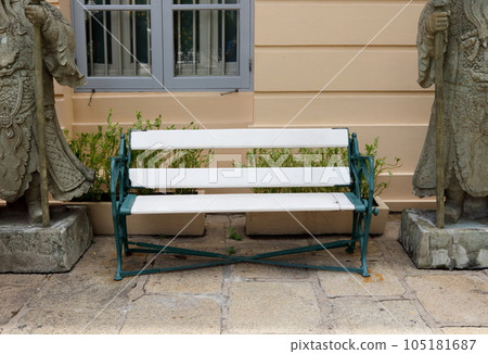 White bench on rock floor beside wall. 105181687