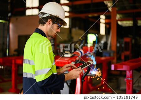 Young industrial engineer holding tablet checking and controlling machine 105181749