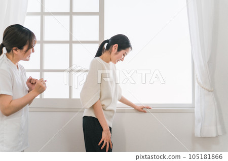 A woman who endures pain in rehabilitation treatment and a smiling nurse (physical therapist/occupational therapist) A woman who endures pain in rehabilitation treatment and a smiling nurse (physical therapist/occupational therapist) 105181866