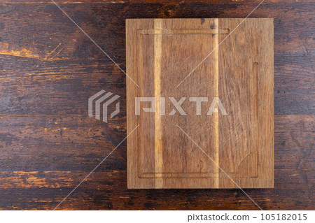 Wooden cutting board on a brown wooden background. Wooden cutting board on a brown wooden background. 105182015