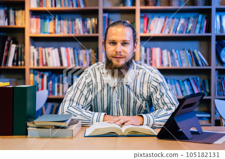 Portrait of man reading books and working in library for education 105182131