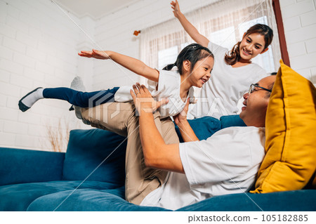 Father mother and daughter doing exercise in living room at home 105182885