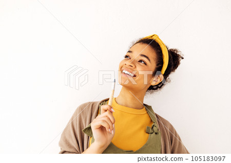 Charming smiling african ethnicity female painter girl, holding brush in her arm 105183097