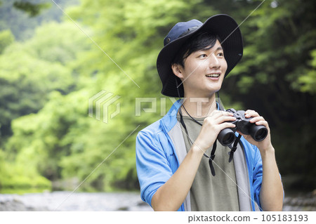 A young man birdwatching on the river bed 105183193