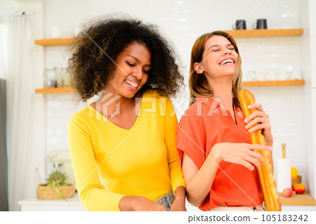 Happy lesbian couple cooking in kitchen at home, Women preparing dinner on first dating, Couple of female lovers spending time together at home, People with good relationship Happy lesbian couple cooking in kitchen at home, Women preparing dinner on first dating, Couple of female lovers spending time together at home, People with good relationship 105183242