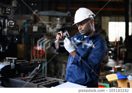 Professional male industrial worker in white hard hat working at manufacturing Professional male industrial worker in white hard hat working at manufacturing 105183282