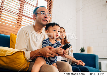 Happy family watching television together at living room 105183494